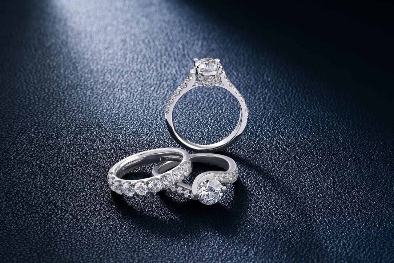 Close-up of luxurious diamond engagement and wedding rings on a textured surface, showcasing elegance and craftsmanship.