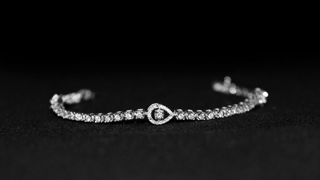 Close-up of a luxurious diamond bracelet with a black backdrop, showcasing elegance.